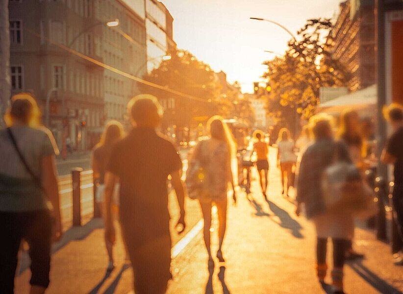 Menschen gehen im Sonnenuntergang über eine Straße