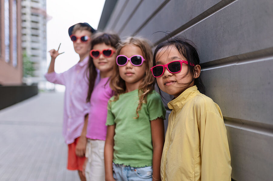 Vier Kinder mit Sonnenbrille stehen in einer Reihe hintereinander